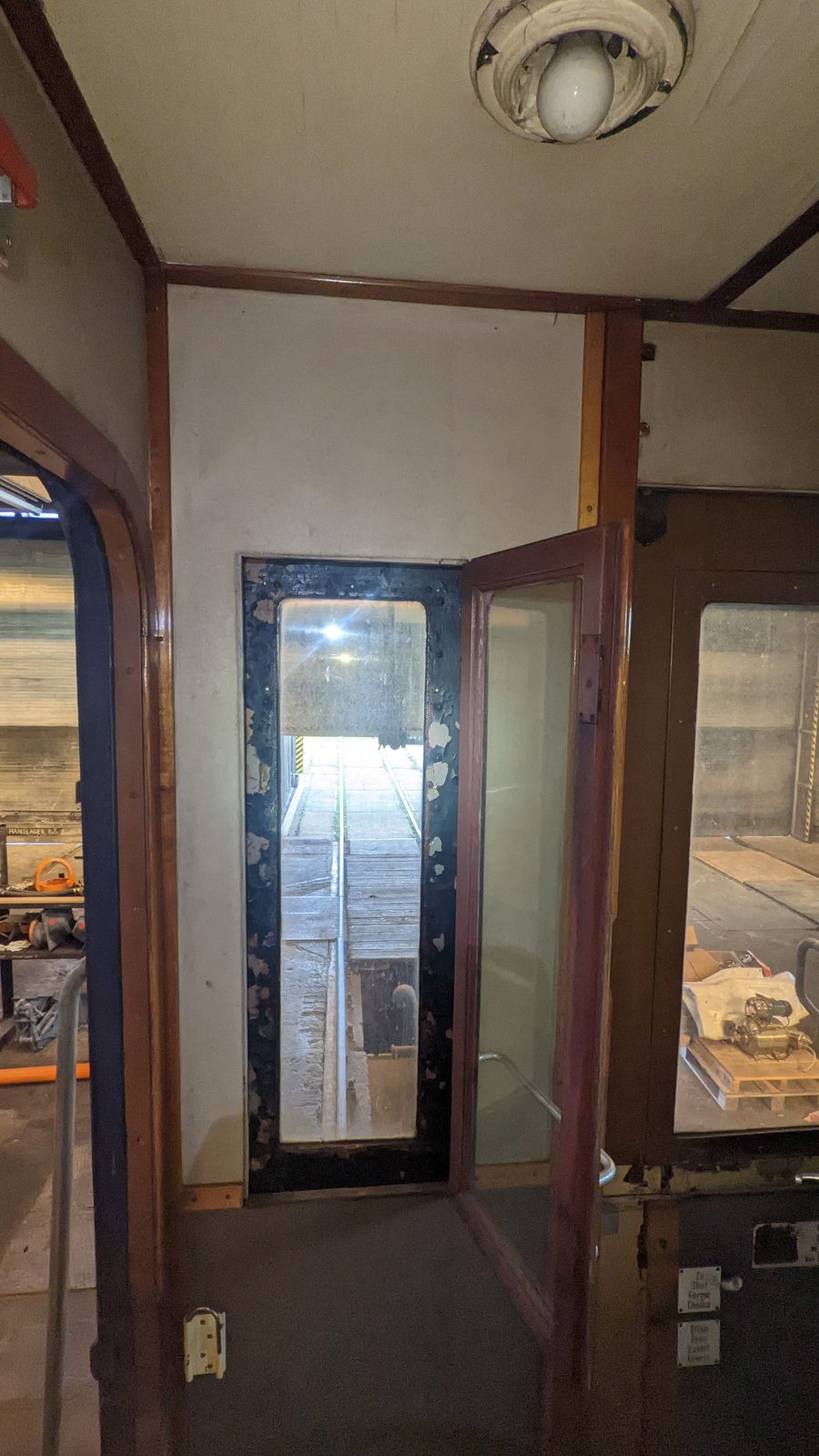 Innenraum eines historischen Wagens mit hölzerner Übergangstür, Blick in die Werkstatt/über die Arbeitsgrube.